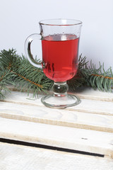 Blue spruce branches on a wooden box of boards, painted in white. Nearby is a glass of red wine.