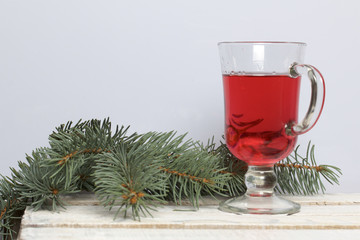 Blue spruce branches on a wooden box of boards, painted in white. Nearby is a glass of red wine.