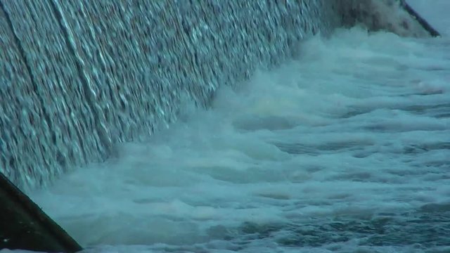 Flowing water through the dam. Waterfall.
