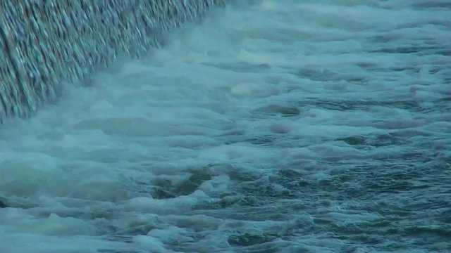 Flowing water through the dam. Waterfall.