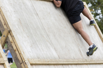 Adventure obstacle course race participant climbing a wall