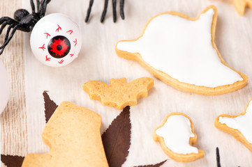 Fresh homemade decorating halloween cookies with ghost, creeping spider, bat, haunted castle and horrifying eyeball on wooden background, copy space