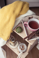 Knitted, warm sweaters, a cup of hot tea, autumn decor, a book, a pumpkin on a wooden chair. Cozy, autumn decor. Autumn interior, sofa. Autumn. Winter.