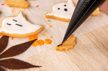 Fresh homemade decorating halloween cookies with ghost, creeping spider, bat, haunted castle and horrifying eyeball on wooden background, copy space