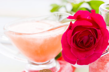 Spa and wellness setting with rose flower, sea salt, oil in a bottle on wooden white background