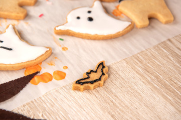Fresh homemade decorating halloween cookies with ghost, creeping spider, bat, haunted castle and horrifying eyeball on wooden background, copy space