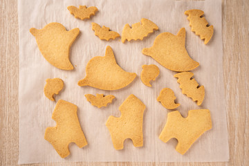 Fresh homemade decorating halloween cookies with ghost, creeping spider, bat, haunted castle and horrifying eyeball on wooden background, copy space