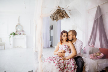 Wedding couple have a photo session in the amazing studio. Young couple hug and kiss while sitting...