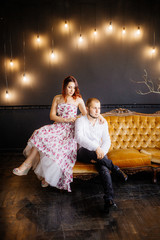 Wedding couple have a photo session in the amazing studio. Young couple hug and kiss while sitting...