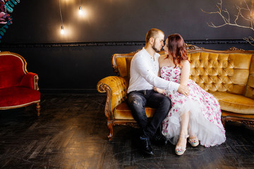 Wedding couple have a photo session in the amazing studio. Young couple hug and kiss while sitting...