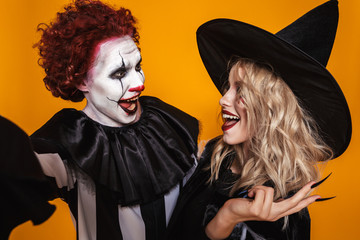 Cheerful scary witch and clown making selfie isolated