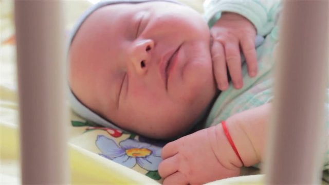 newborn sleeping in bed,a little baby sleeping in a crib through the partition