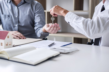 Real estate Sales manager giving keys to customer after signing rental lease contract of sale purchase agreement, concerning mortgage loan offer for and house insurance