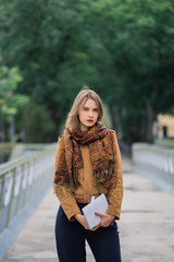 A very beautiful girl is standing on an iron bridge and is posing on the camera.