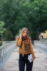 A very beautiful girl is standing on an iron bridge and is posing on the camera.