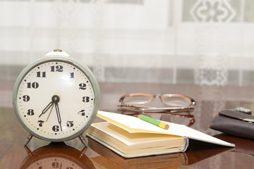 old metal alarm clock, glasses, book, wallet on the table near t