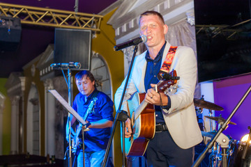 Musician plays bass guitar and singer on stage in neon light