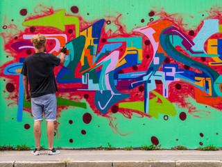 young man use his talent and feeling for art to apply this with various colors to a city wall