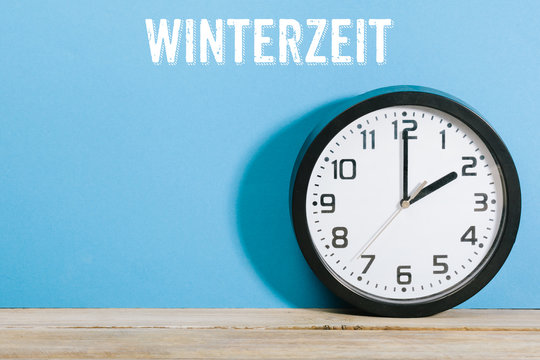Winterzeit Text auf Wand mit Uhr auf Tisch um 2 Uhr morgens