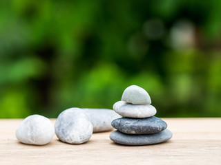 Four stones stacked placed on a wooden board. The backdrop is black on green.