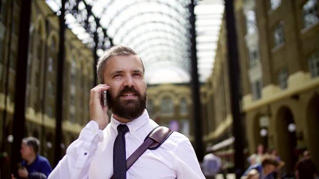 Businessman with smartphone on the trian station in London, making a phone call.