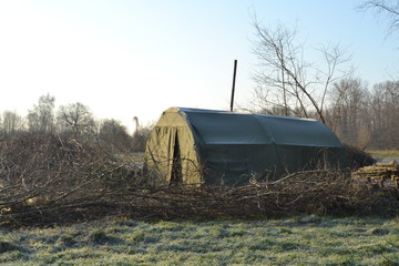 groene tent met houtkachel van bosarbeiders bij winteronderhoud in natuurgebied De Witte Brink in de Achterhoek