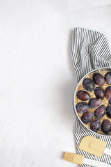 Autumn baking concept - Uncooked Plum piein metal mold, silicone spatula, basting brush on Crumpled...