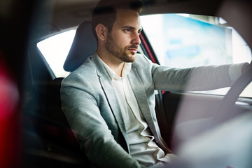 Handsome elegant serious man drives a car