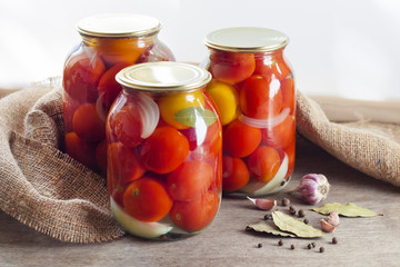 Glass jars with red pickled tomatoes, sealed with metal lid
