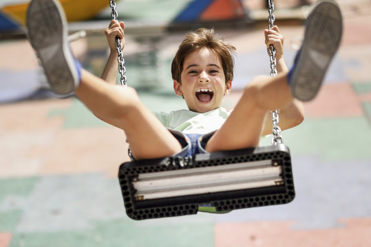 Portrait of screaming little girl having fun on a swing