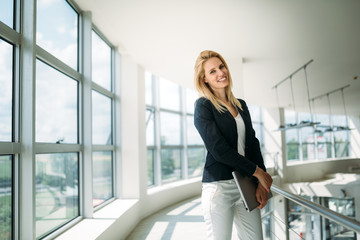 Portrait of young busineswoman standing in office lobby.