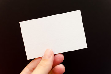 Fototapeta premium Hand holding a blank business card on a black background