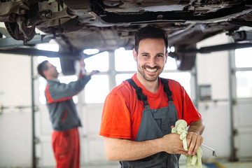 Profecional car mechanic changing motor oil at maintenance repair service station