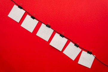 Six paper sheets attached with a binding clip, located diagonally on red background