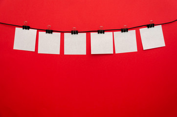 Six paper sheets attached with a binding clip in the center of red background