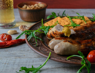 brown dish with grilled sausages with mustard and arugula. on a wooden background
