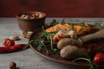 brown dish with grilled sausages with mustard and arugula. on a wooden background