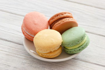 Colorful macaroons cakes on plate. Plate with macaroons on wooden background