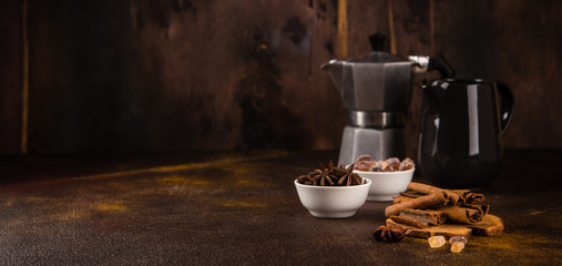 Coffee pot with spices on brown background.