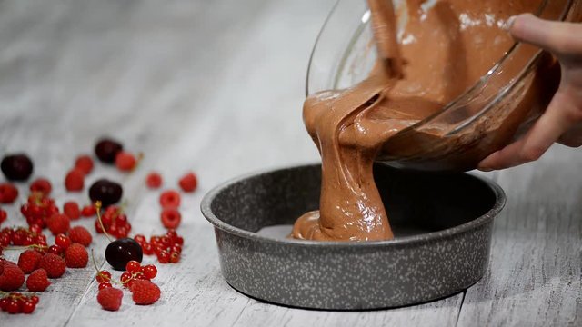 Pouring chocolate batter into cake pan.