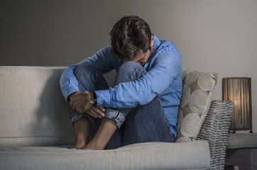 young attractive and handsome sad latin man sitting tired and depressed at home sofa couch feeling overwhelmed and worried suffering depression crisis and anxiety