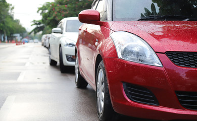 Closeup of front side of modern red car park in parking area in rainy day. 