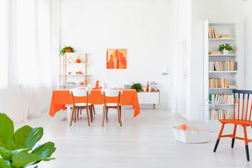 Open space area of white and orange colored living room interior in modern home.
