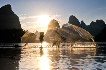 Aalscholvervisser op zijn bamboevlot bij zonsondergang