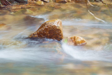 blurry water flowing on the rock and wave splashing in river