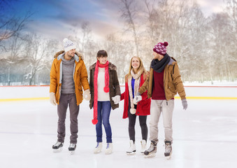 people, friendship, sport and leisure concept - happy friends on outdoor skating rink