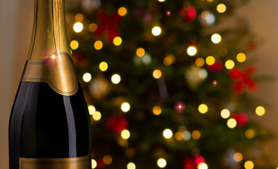 drink, alcohol, advertisement and holidays concept - close up of bottle of champagne with blank golden label over christmas tree lights background