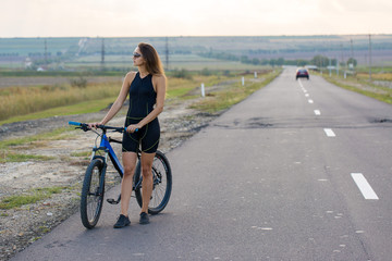 Girl on a mountain bike on offroad, beautiful portrait of a cyclist at sunset