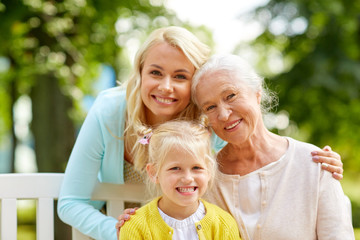 family, generation and people concept - happy smiling woman with daughter and senior mother sitting...