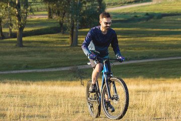 Naklejka premium A cyclist rides the hills, Beautiful portrait of a guy on a blue bicycle